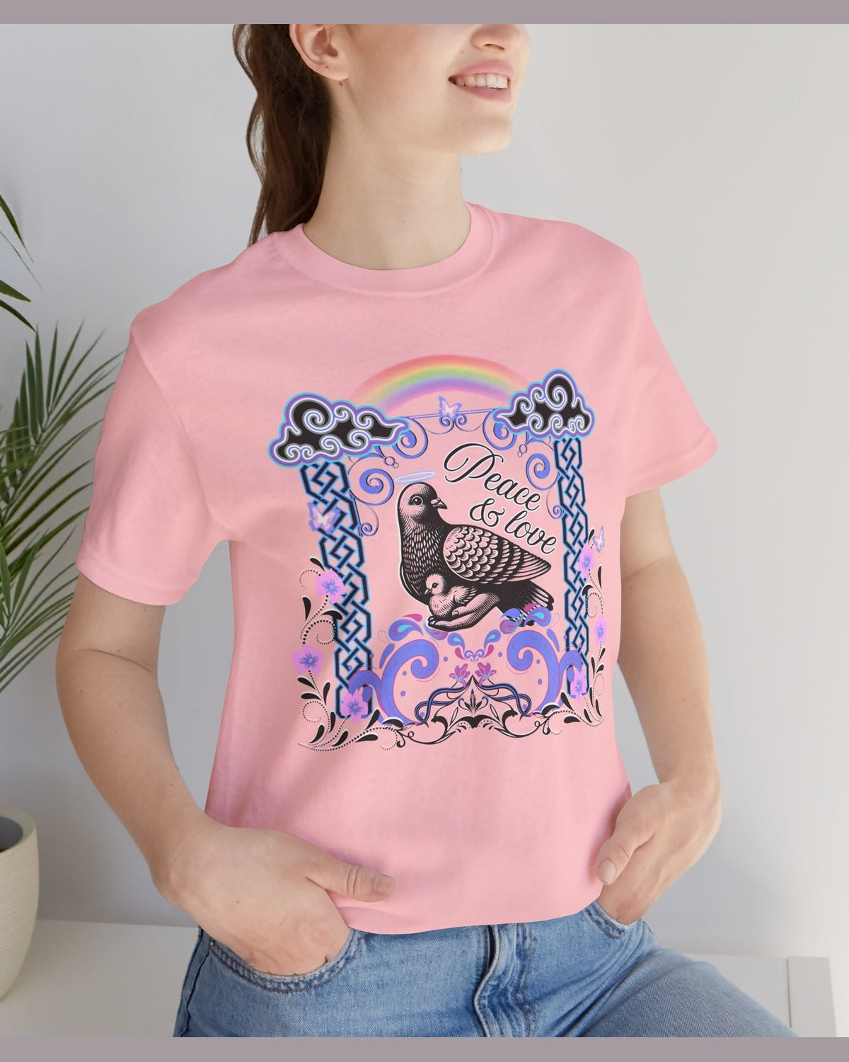 Person wearing a pink t-shirt with a graphic design featuring a dove and text Peace & Love.