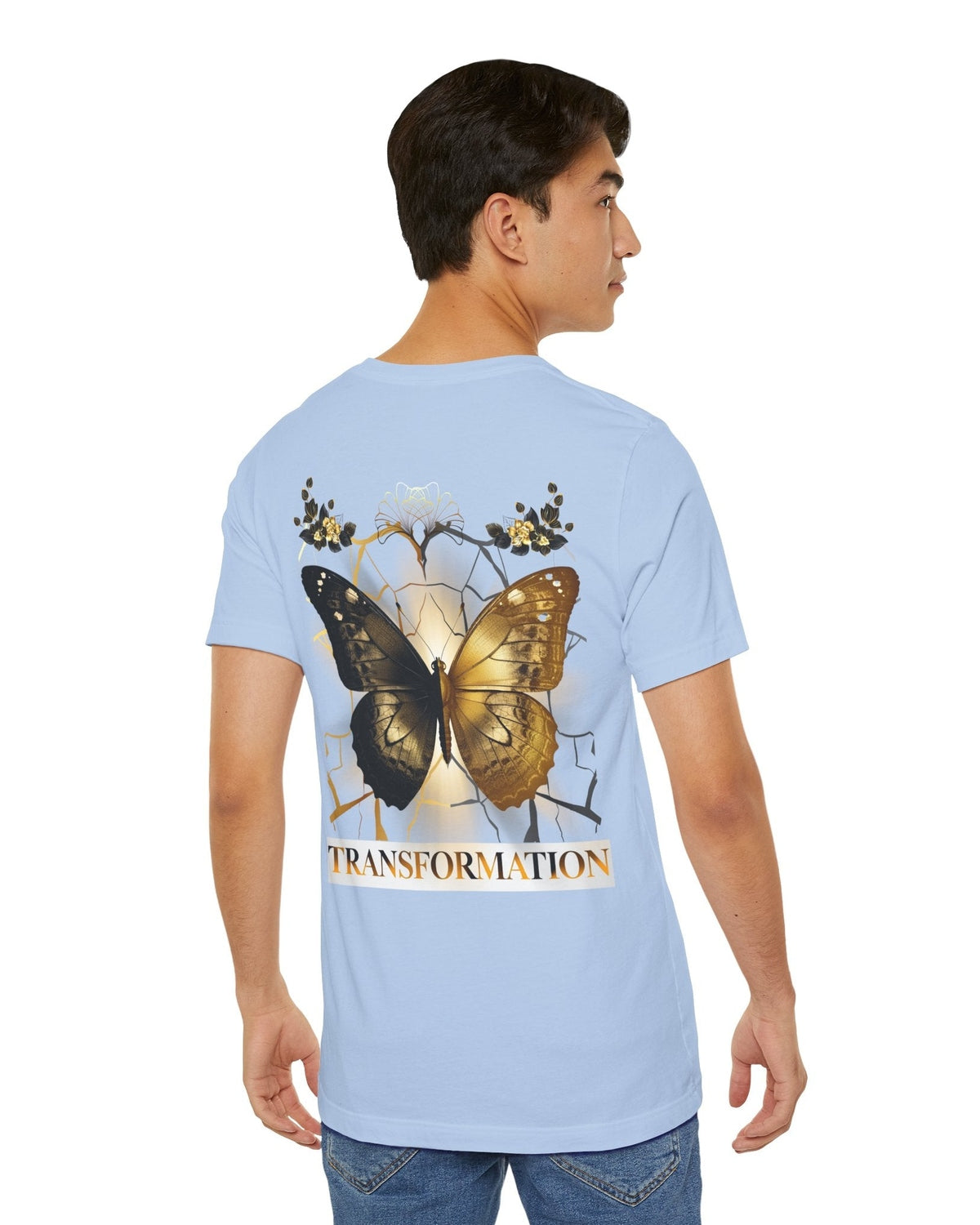 Light blue t-shirt with gold and brown butterfly design and 'TRANSFORMATION' text on a white background