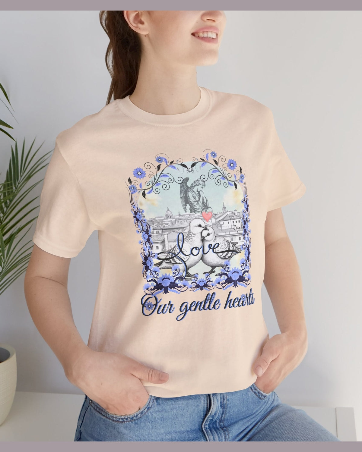 Person wearing a beige t-shirt with a graphic pigron design and text Love our gentle hearts.