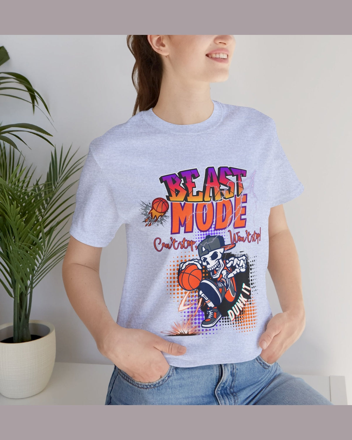 Person wearing a t-shirt with 'Beast Mode Cant Stop Wont Stop' graphic design of basketball skeleton, standing indoors next to a plant.
