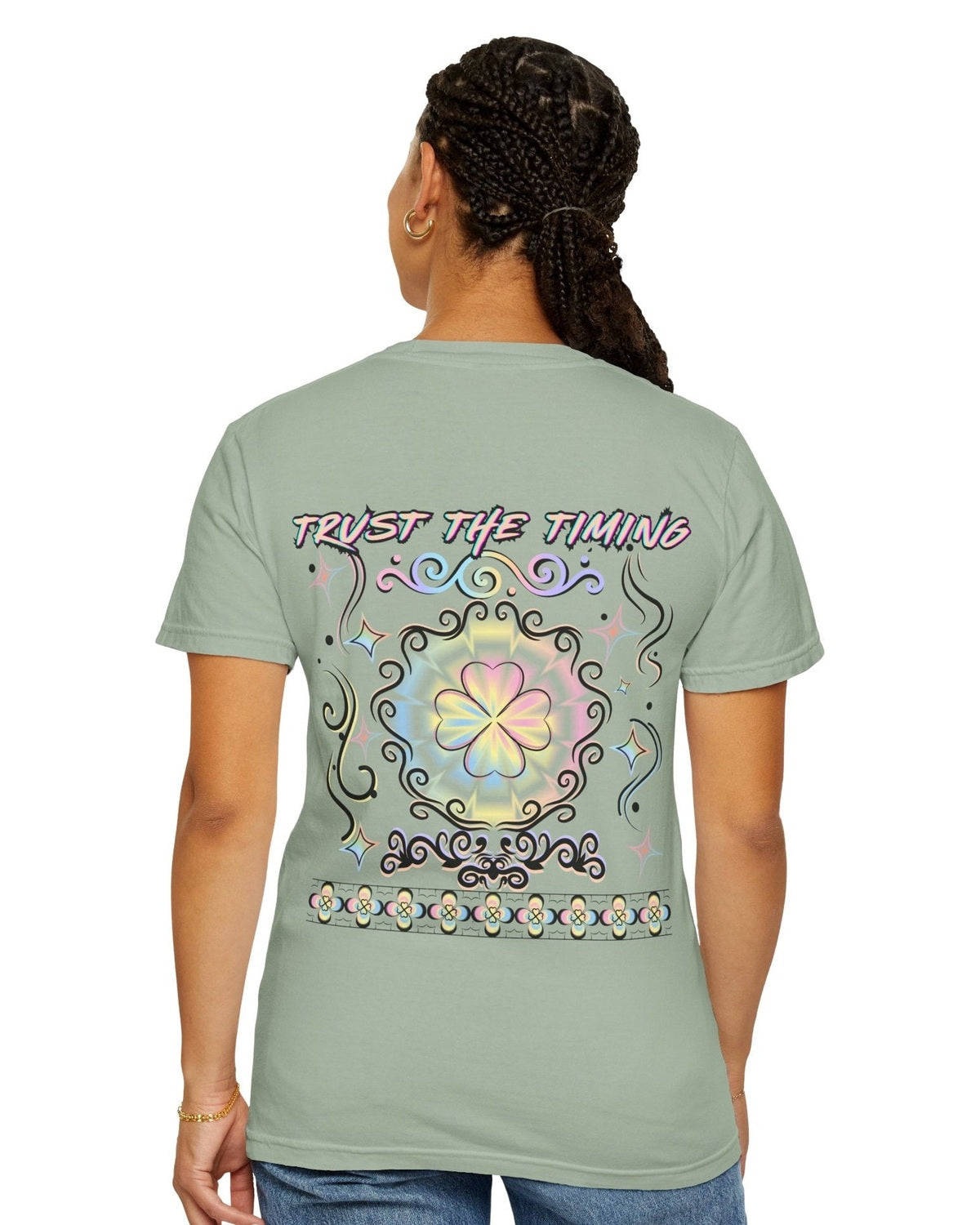 Woman is wearing a light green t-shirt with a colorful graphic four leaf clover design and a text trust the timing on a white background