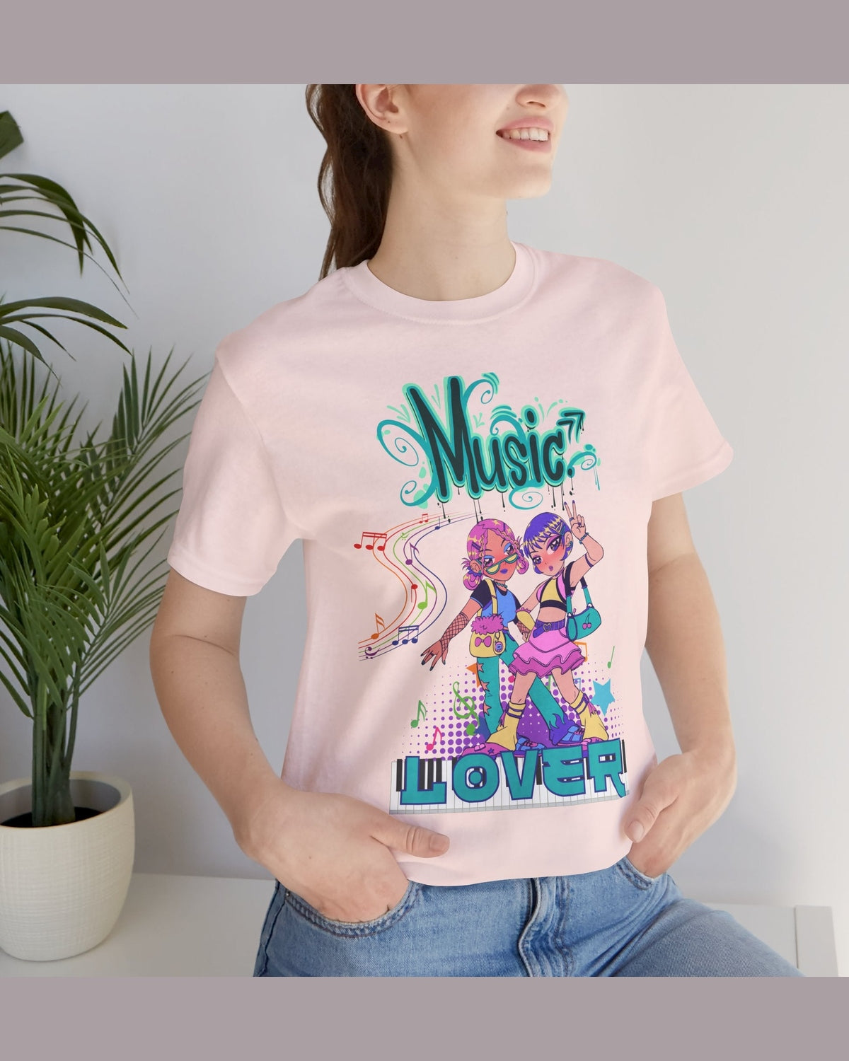 Person wearing a pink t-shirt with 'Music Lover' featuring two dancing Anime girls design, standing next to a plant.
