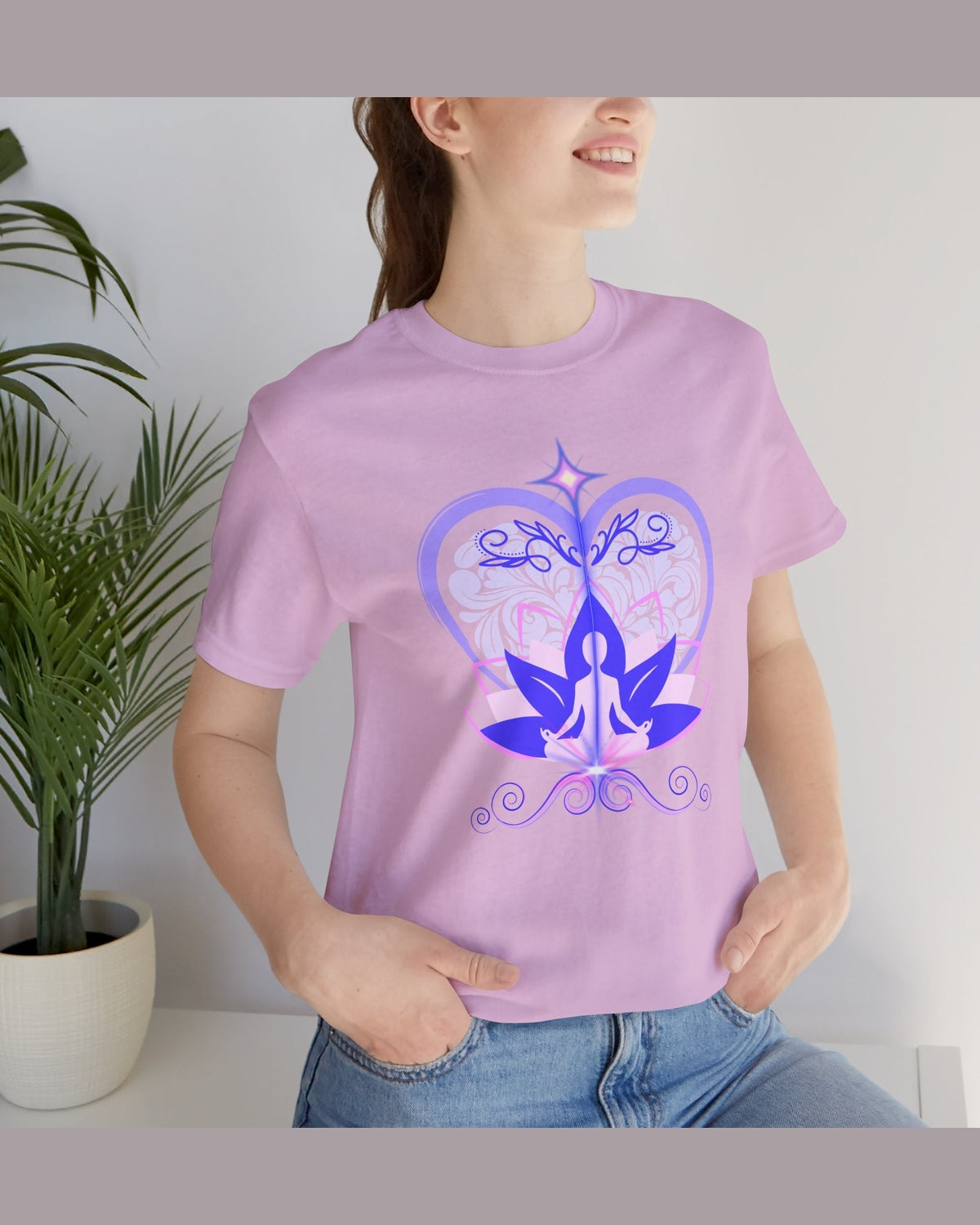 Person wearing a purple t-shirt with a yoga-themed design, standing indoors next to a plant.
