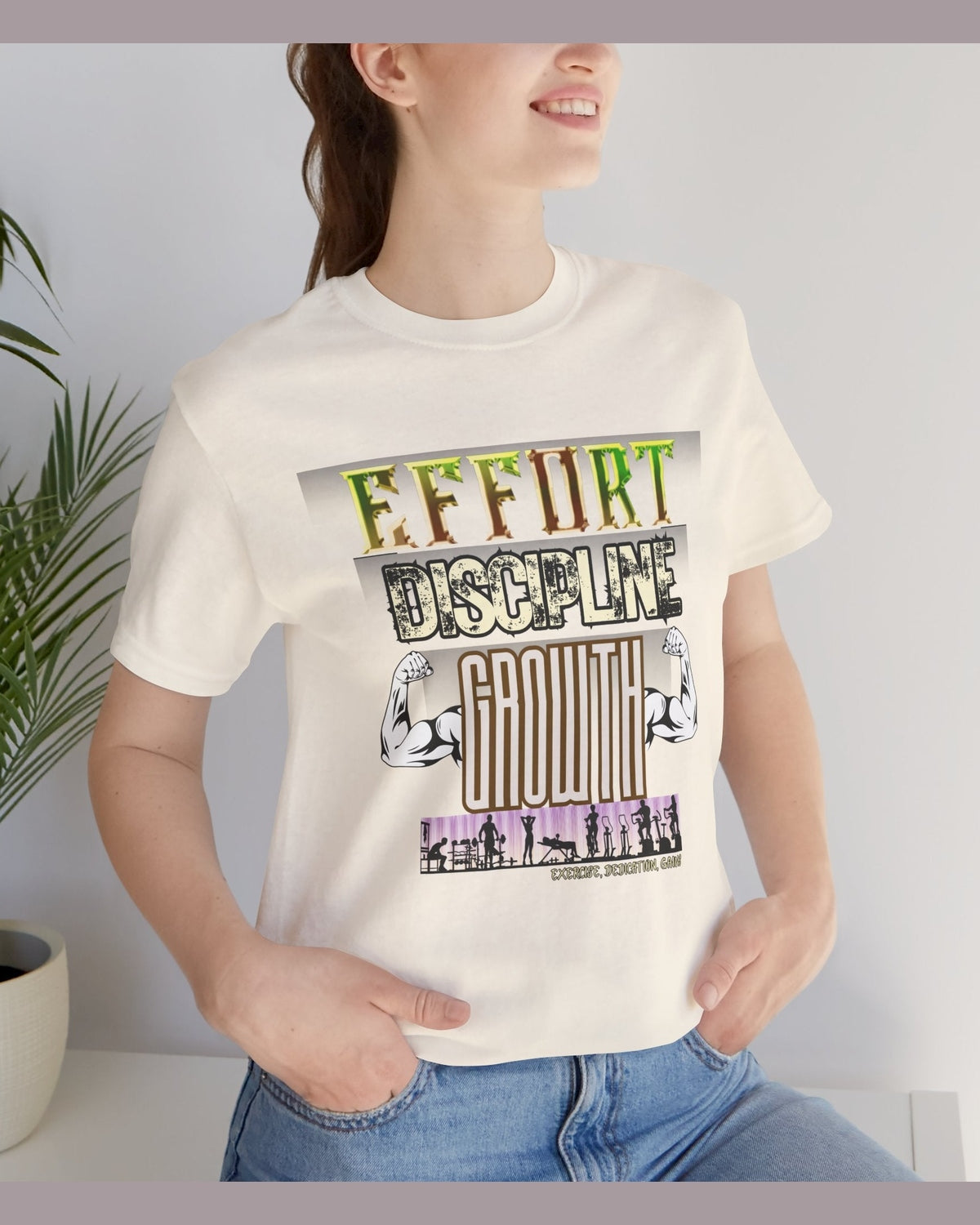 Person wearing soft yellow t-shirt with motivational gym text 'Effort Discipline Growth' and flexing arms graphic, standing against a light gray background.