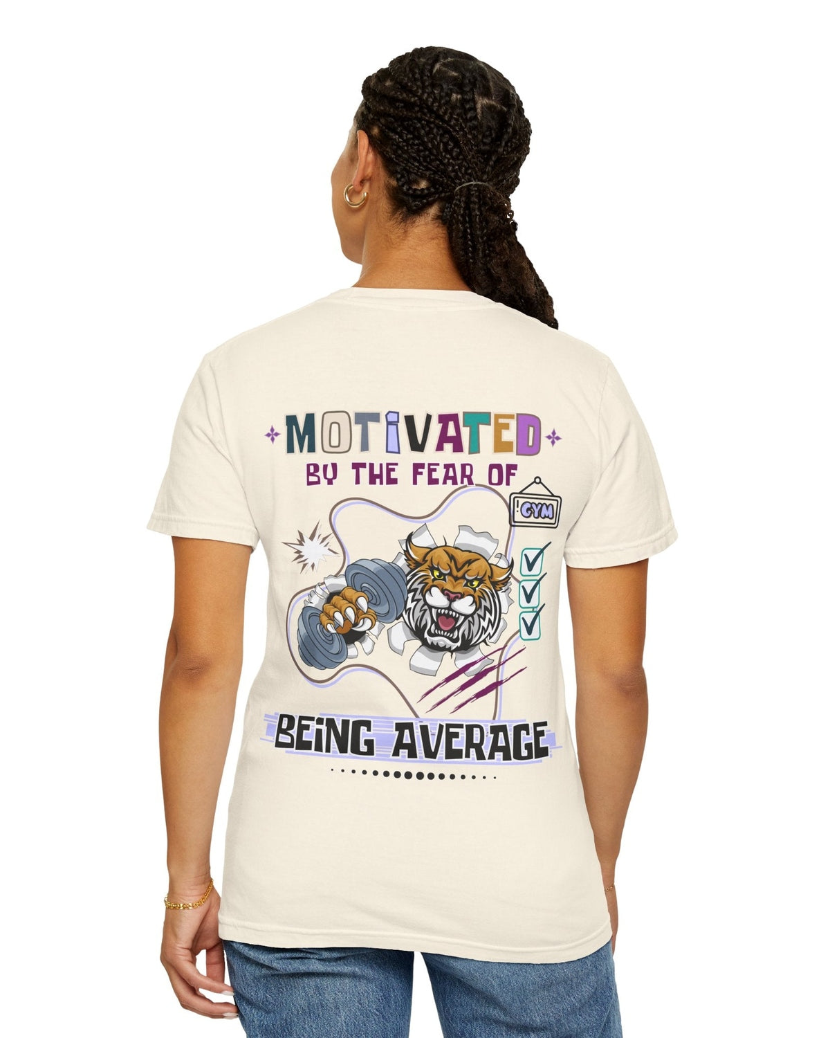 Person wearing a cream t-shirt with a motivational tiger graphic and text Motivated by the fear of being average on the back.