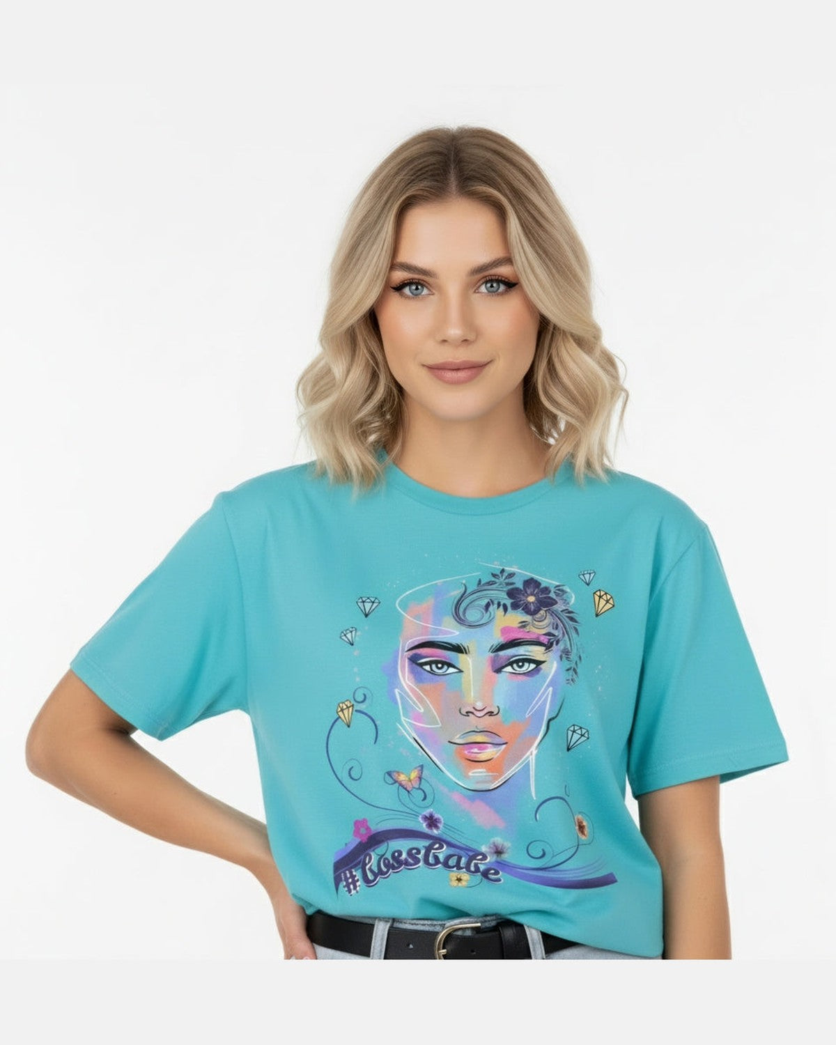 Woman wearing a turquoise t-shirt with a colorful graphic design of a female face, diamonds and flowers and a text #bossbabe on a white background