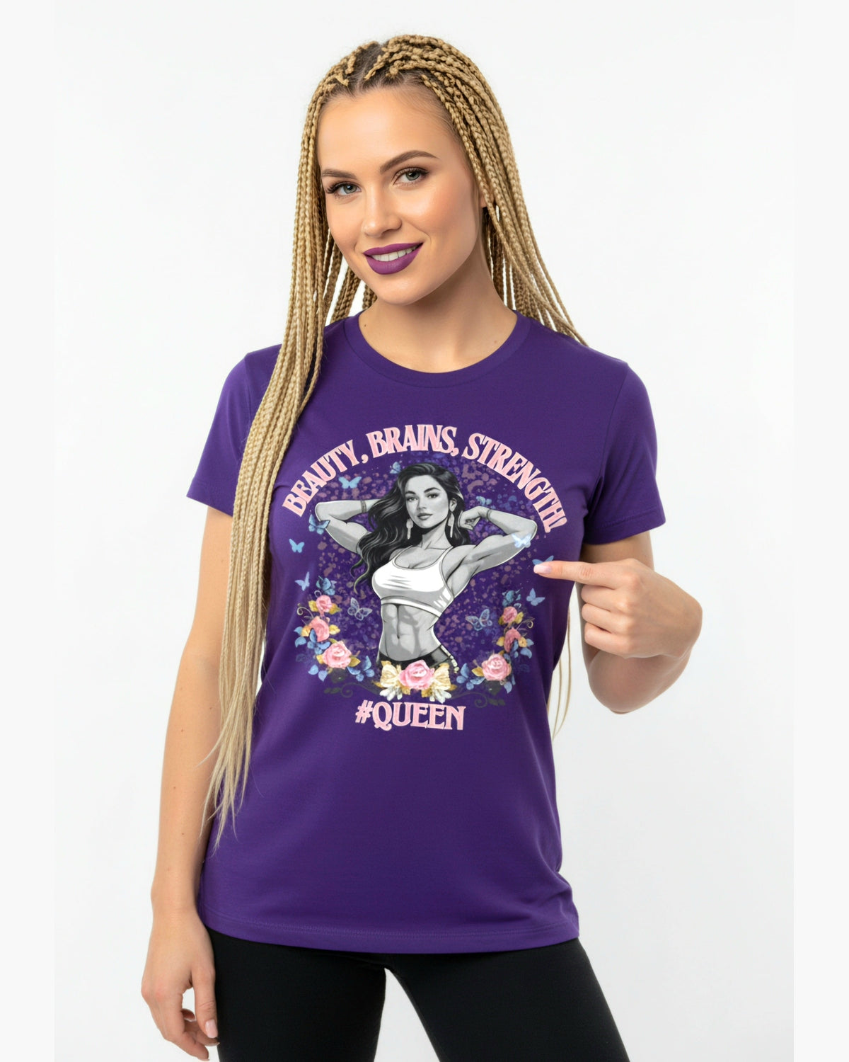 Woman wearing a purple t-shirt with graphic fitness design and text Beauty, Brains, Strength #Queen pointing to the shirt.