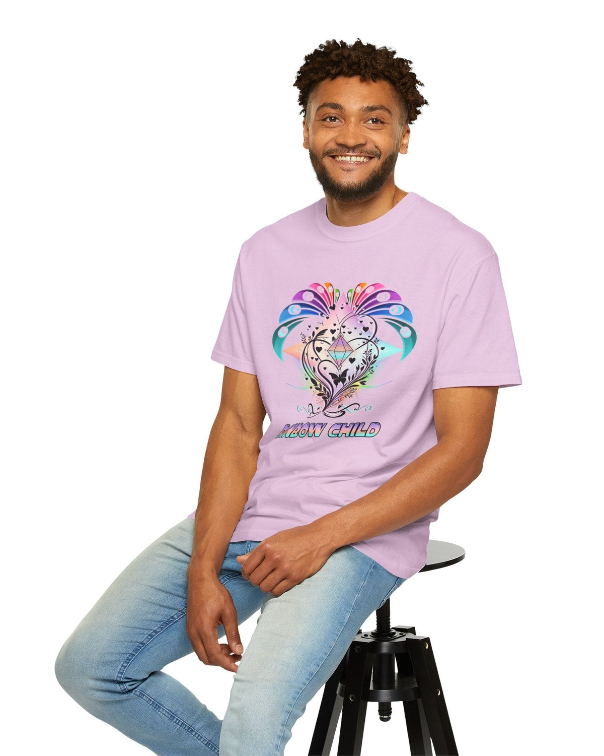 Man wearing a pink t-shirt with a colorful graphic design sitting on a stool against a white background