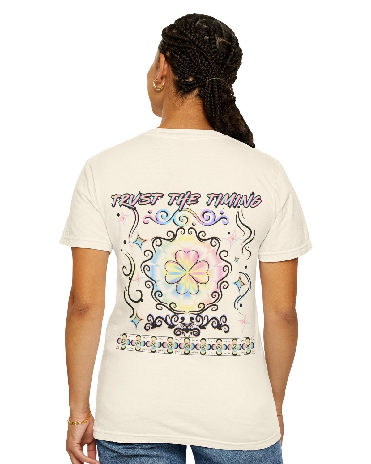 Woman wearing a light yellow t-shirt with a colorful graphic four leaf clover design and a text trust the timing on a white background