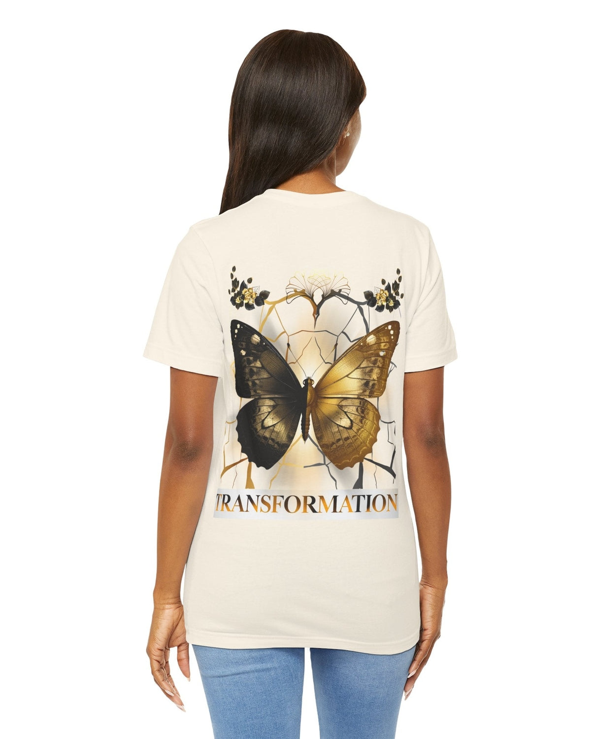 Person wearing a cream t-shirt with a gold and brown contrast butterfly design and 'TRANSFORMATION' text on the back.