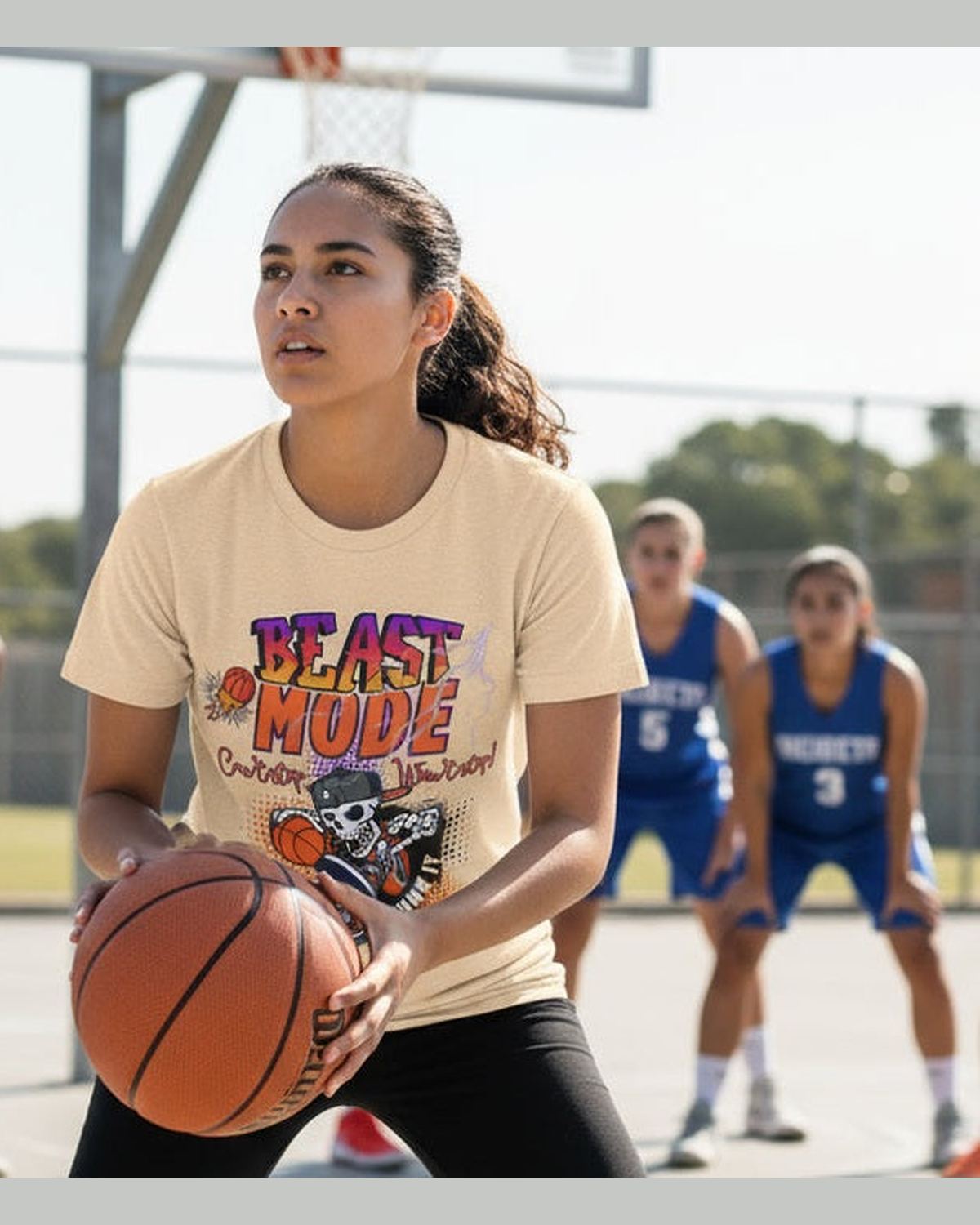 A woman wearing caramel t-shirt with a skeleton holding a basketball and 'Beast Mode Cant Stop Wont Stop' text at a basketball court