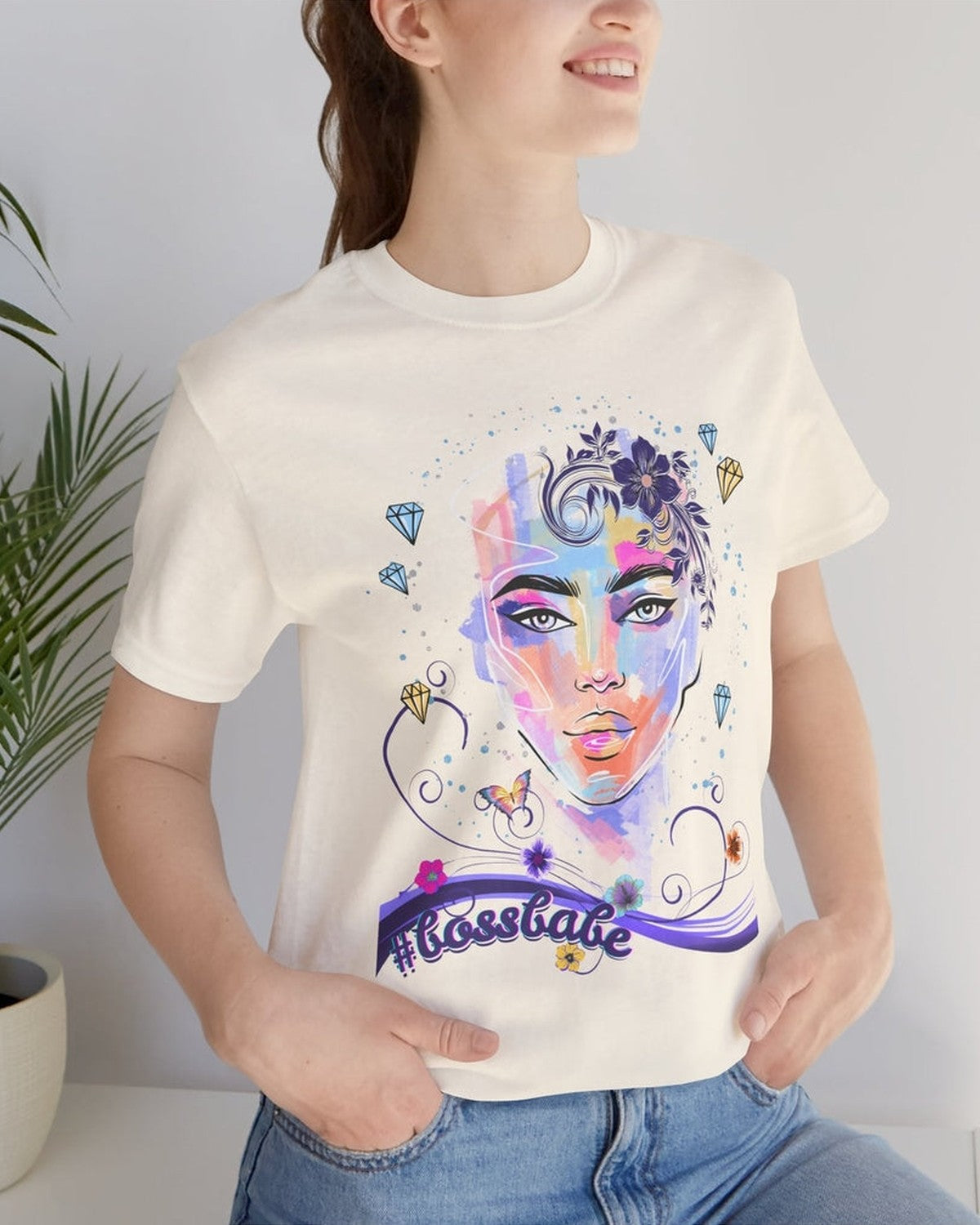 Person wearing a soft yellow t-shirt with a colorful graphic design of a female face, diamonds and flowers and a text #bossbabe on a white background