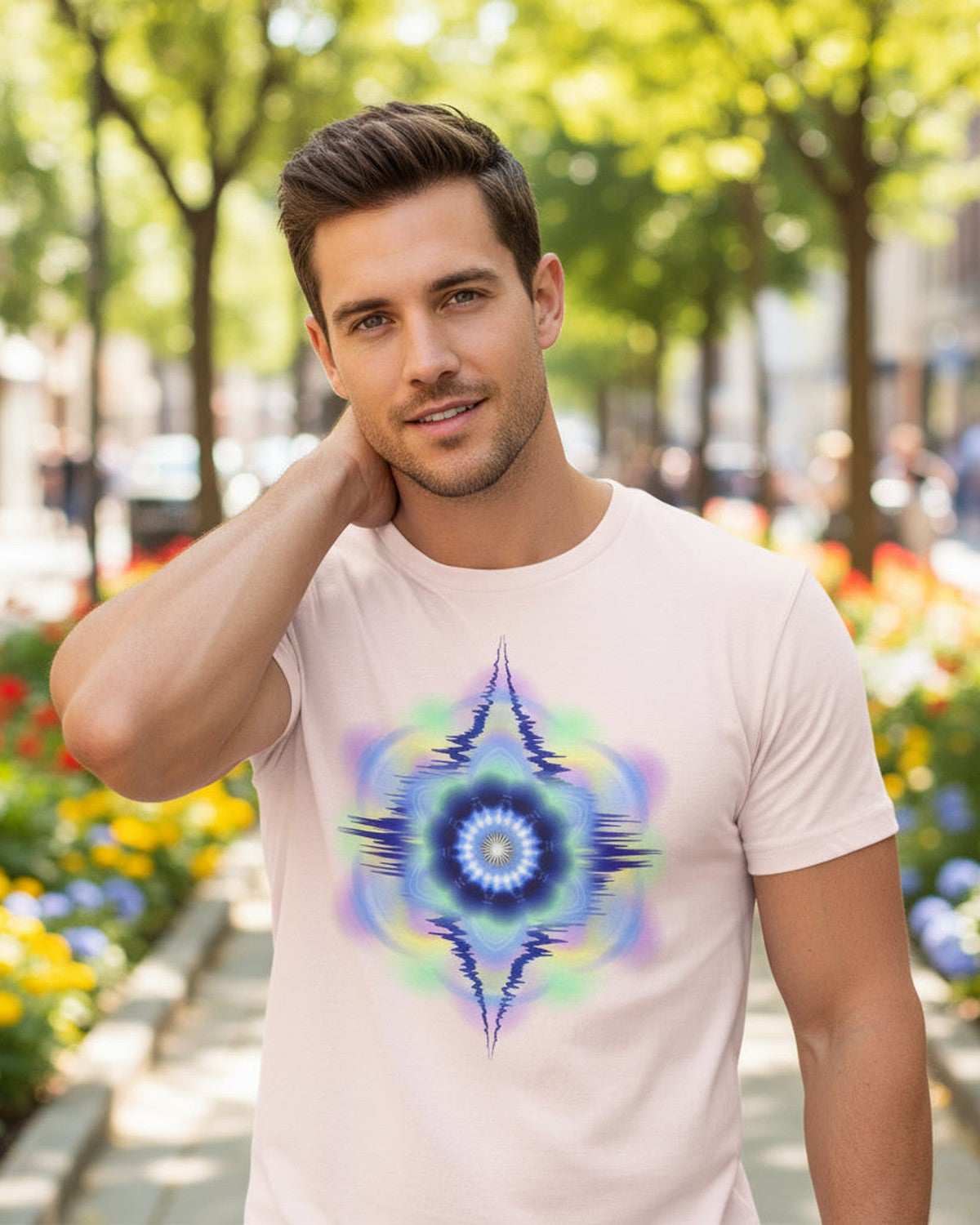 Man wearing a pink t-shirt with a colorful abstract design and a colorful garden behind