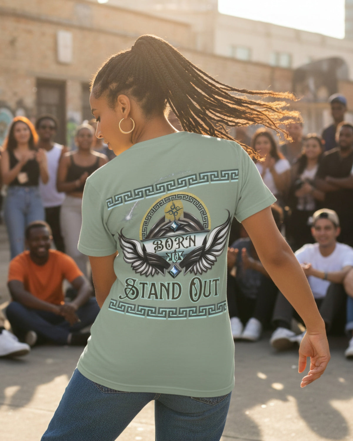 Woman wearing a green t-shirt with a wing graphic design and text Born to Stand Out on the back, dancing in front of a crowd.