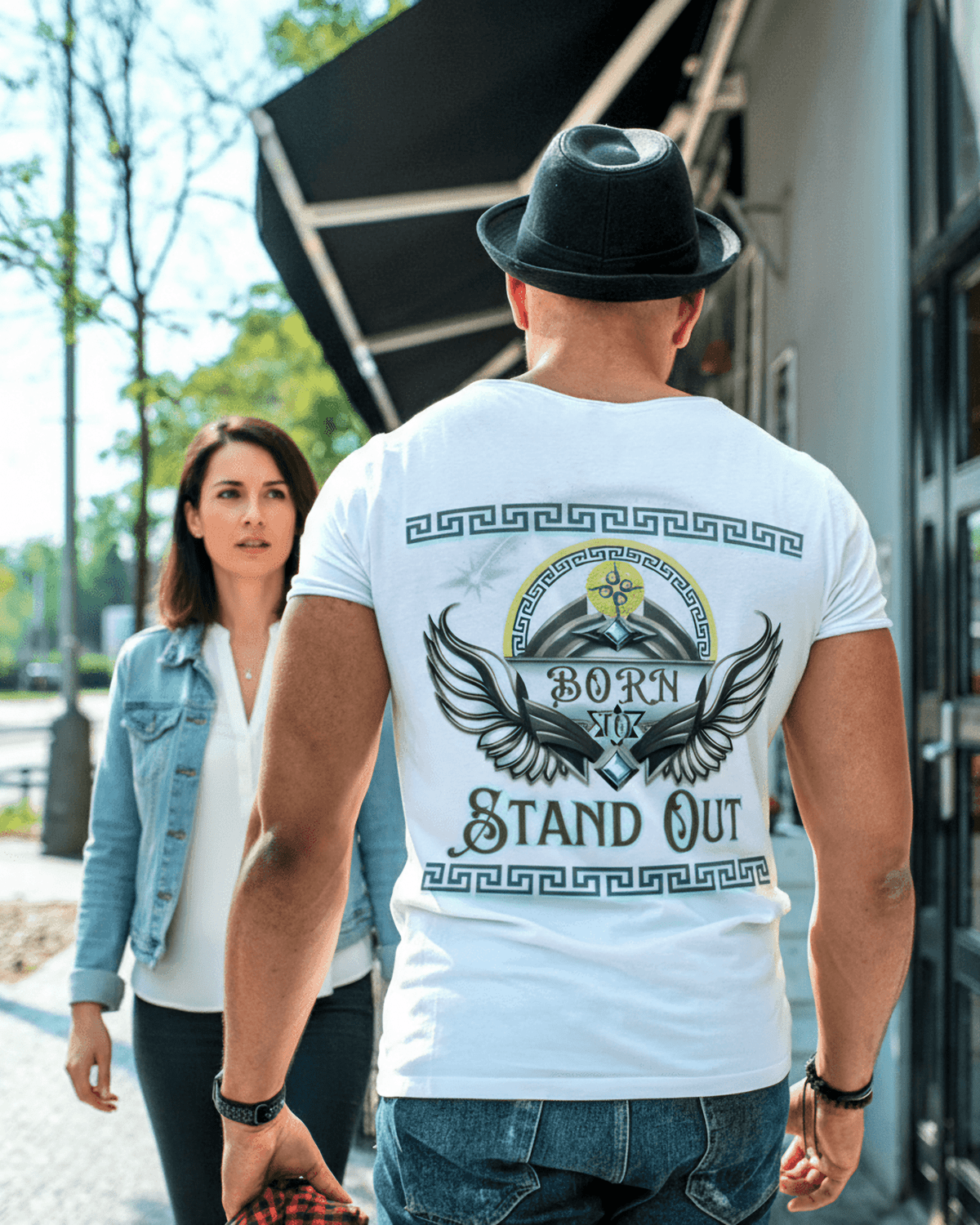 Man wearing a white t-shirt with 'Born to Stand Out' design, walking outdoors.